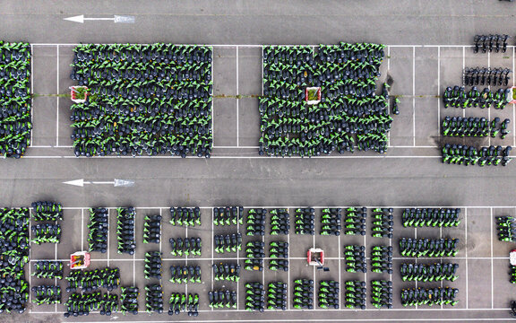 Aerial view of a large parking lot filled with rows of green electric scooters in Middenmeer, North Holland, Netherlands.