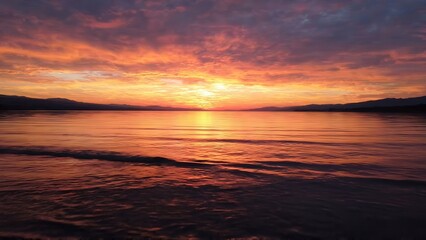 Fototapeta premium Vibrant sunset over calm water with colorful clouds reflecting on the surface, creating a serene atmosphere in a natural landscape at dusk