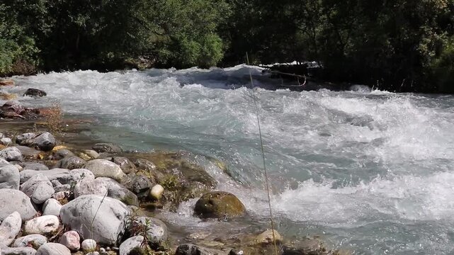Wild b-roll: Raging, turquoise Sairam-Su river rapids flow over stones and pebbles in Shymkent. Powerful nature and adventure in a lush mountain landscape.