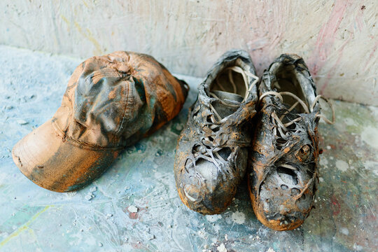 Close up of burned baseball cap and melted sneakers resting on studio floor, showing destruction and creative process. Useful for fire damage, loss, insurance claim, safety campaign concepts