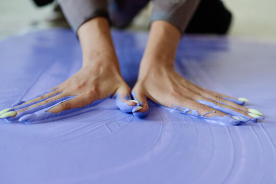 Close up of young adult woman hands spreading purple paint on canvas, creating contemporary artwork and expressing creativity. Ideal for art practice, creative process, design branding