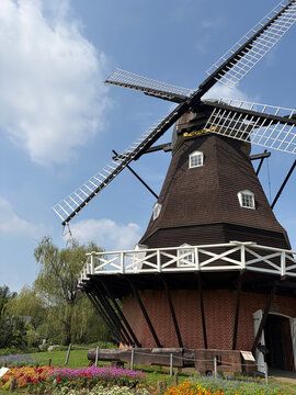 Dutch style windmill and flower bed against a blue sky