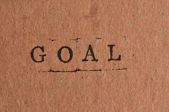 Word GOAL stamped in dark ink centered on brown recycled paper texture for business marketing.