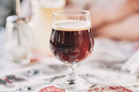 Close-up of a glass of dark craft beer with frothy foam on top