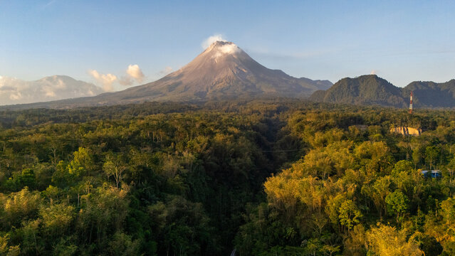 Aerial view of the majestic Mount Merapi volcano rising above the lush tropical forests of Tunggularum in Kecamatan Turi, Daerah Istimewa Yogya, Indonesia.