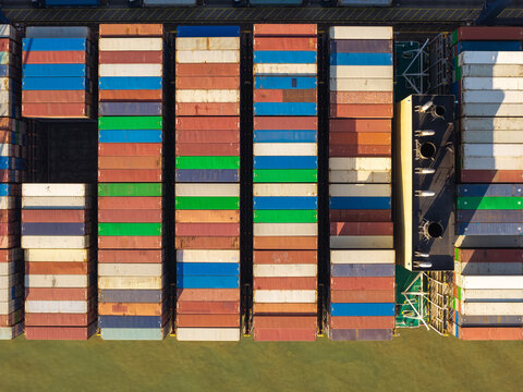 Aerial view of colorful shipping containers stacked on a cargo ship deck with geometric patterns and industrial textures in United Kingdom.