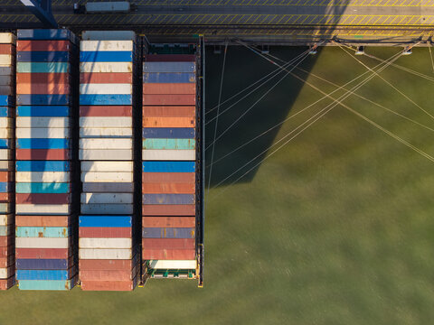 Aerial view of a cargo ship loaded with colorful shipping containers docked at a port in the United Kingdom.