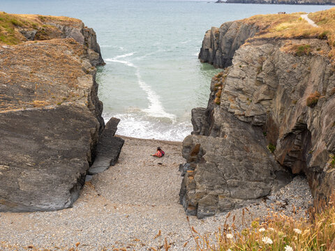 Woman sat down isolated on a pebble beach