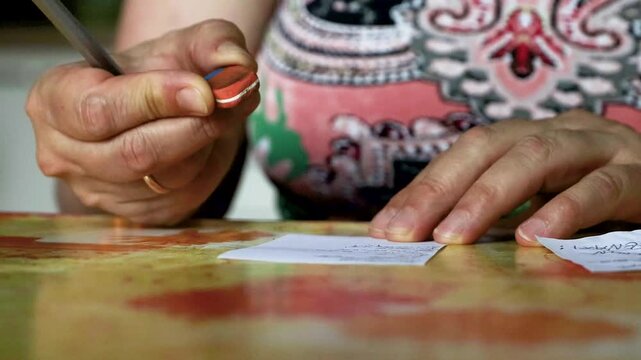 Hand using eraser to correct handwritten notes on small paper cards
