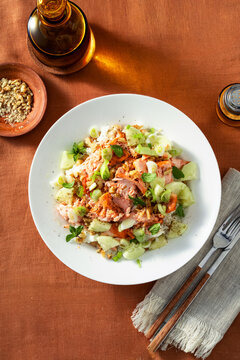 Baked salmon salad with cucumbers, chickpeas, walnuts, feta and rice served on a summer style dining table