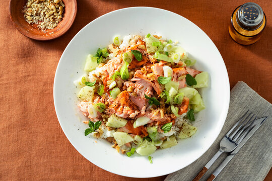Baked salmon salad with cucumbers, chickpeas, walnuts, feta and rice served on a summer style dining table