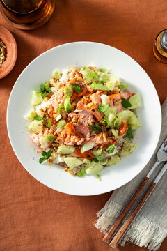 Close up of baked salmon salad with cucumbers, chickpeas, walnuts, feta and rice on a summer style dining table