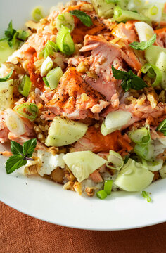 Close up of baked salmon salad with cucumbers, chickpeas, walnuts, feta and rice on a summer style dining table