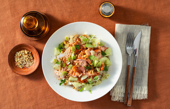 Baked salmon salad with cucumbers, chickpeas, walnuts, feta and rice served on a summer style dining table