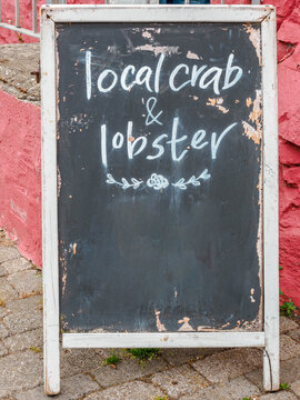 sandwich board with sign written mmenu option of lobster and crab on the beach