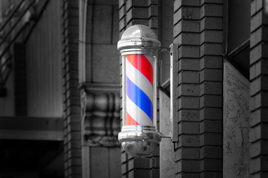 Barber shop sign spinning pole red white and blue on brick wall used to advertise services of Barber Shop