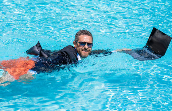 Funny crazy businessman rest in formal wear in pool. Businessman in suit with laptop in swimming pool. Crazy business man summer vacation. Remote working. Summer business vacation. Business trip