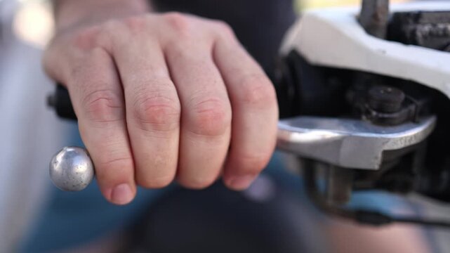 Close up of bare male hand squeezing metal brake lever on motorcycle handlebar. Detail of rider fingers holding scooter brake handle, transportation safety control concept.