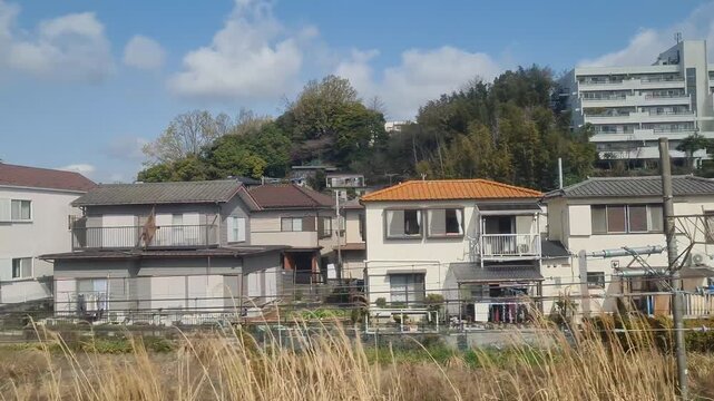 Hillside residential neighborhood in Japan with modern apartments and houses under cloudy sky.
