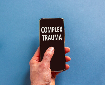 Complex trauma words symbol. Concept words Complex trauma on beautiful black mobile phone screen. Beautiful blue background. Psychologist hand. Psychological complex trauma support concept. Copy space