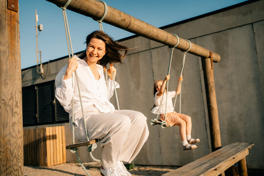 Smiles Shared on Swings During Sunny Afternoon at Local Playground
