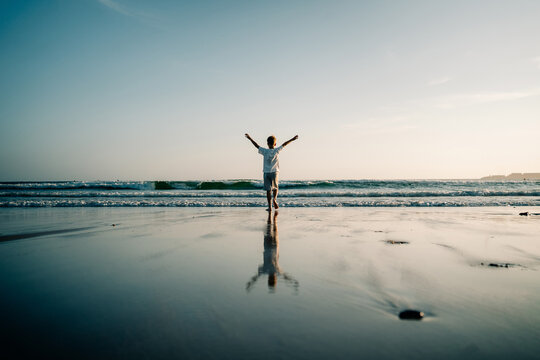 Boy Walks on Beach and Enjoys the Ocean View During Sunset
