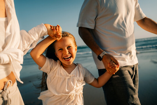 Family Enjoys Time at the Beach While Holding Hands With a Child