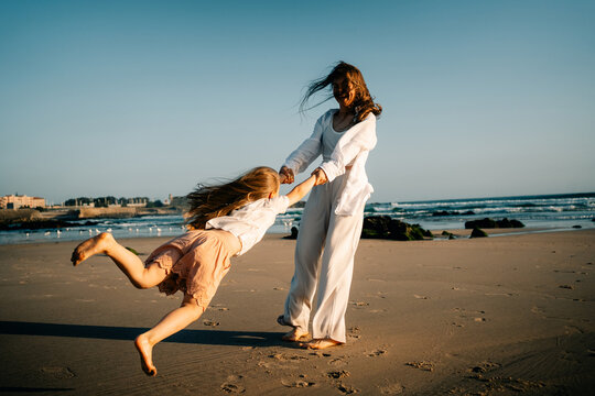Mother and Child Play on a Sunny Beach During the Late Afternoon