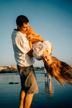 Father Lifts Daughter Happily at the Beach During Sunset Time