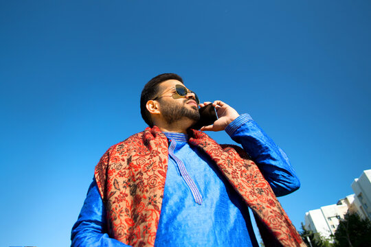 Portrait of Indian man talking by phone in traditional clothes.