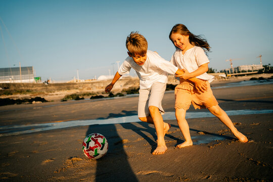 Kids Play Soccer on Beach During Sunset in Seaside Location