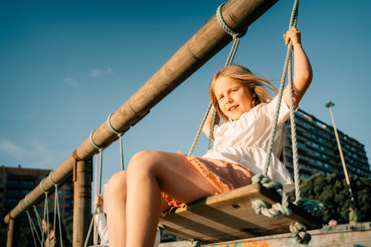 Girl Swings on Playground in City During Sunny Afternoon