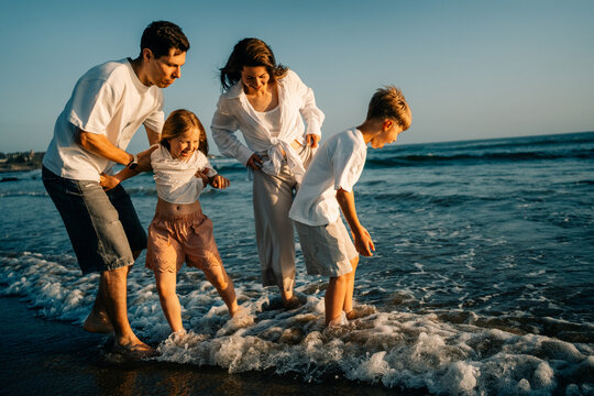 Family Plays Together at the Beach in the Evening Light