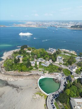 Aerial view of the coastline of Dinard featuring the seawater pool at Plage du Prieure, historic villas, and lush greenery overlooking the English Channel in Dinard, Brittany, France.