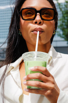 Woman drinking matcha tea outdoors in summer sunlight