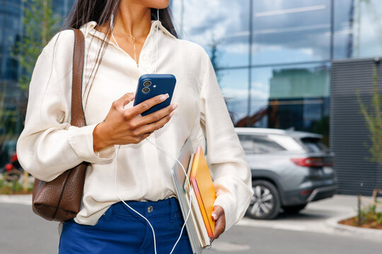 Woman using smartphone with earphones in city street