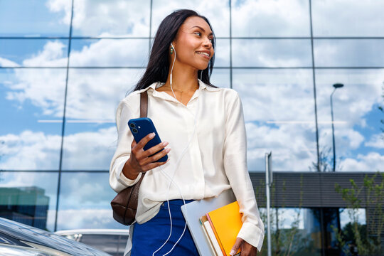Woman with smartphone and folders in downtown area