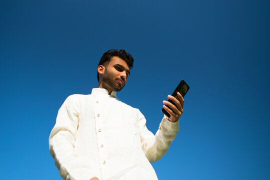 Portrait of Indian man using phone in traditional clothes.