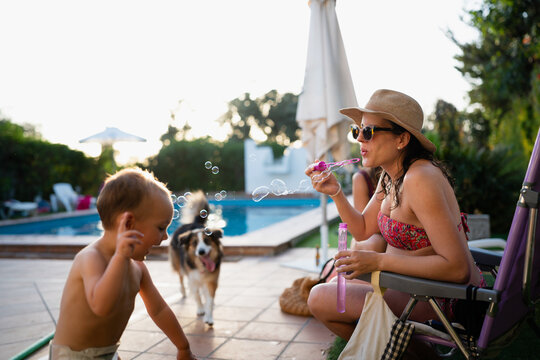 Mother blowing bubbles for happy child and dog