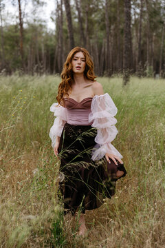 Redhead woman posing in long grass outdoor 