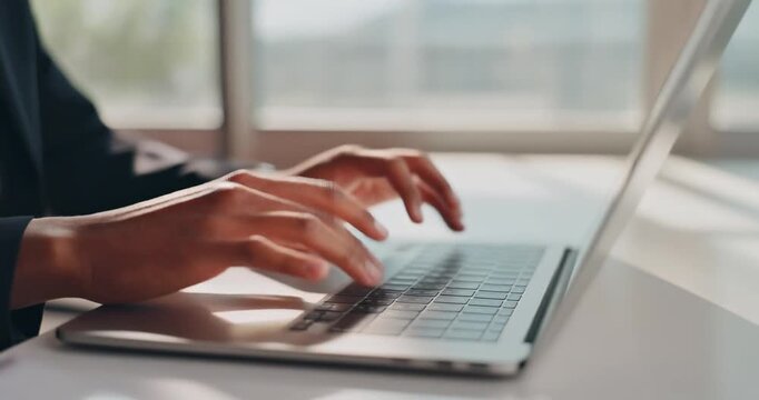 Businessman hands typing laptop keyboard in bright office