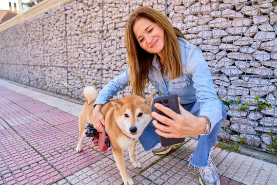 Mature woman taking selfie with shiba inu dog