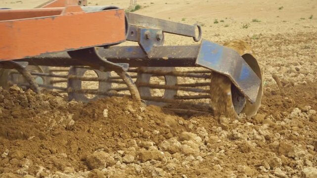 Agricultural harrow cultivating a dry field for seeding