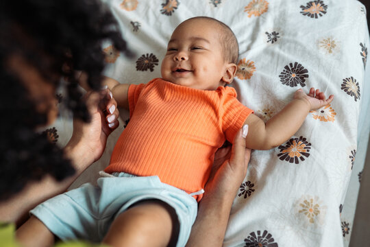 Happy diverse baby smiling while playing with parent
