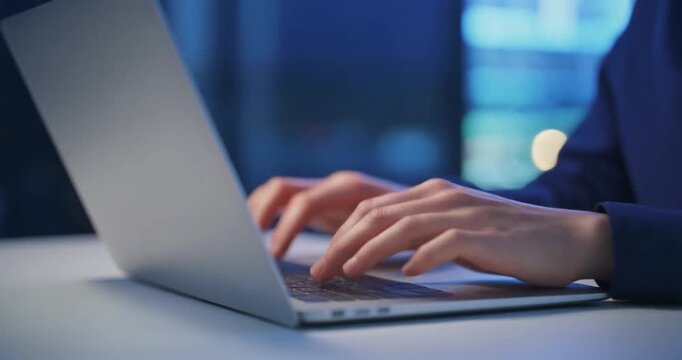 Business professional typing on a modern laptop computer in night office