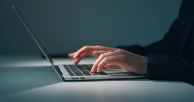 Business person typing on a laptop computer during late night office shift