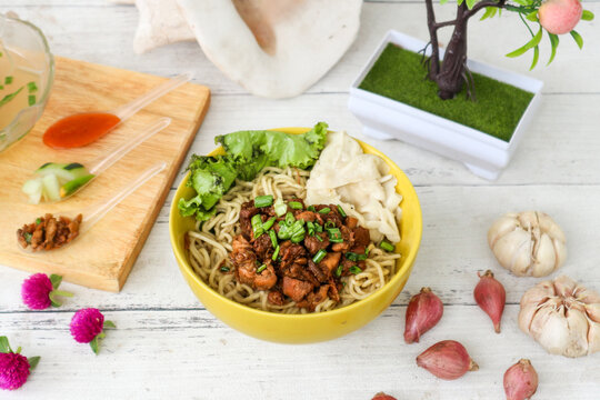 A bowl of chicken noodles, or mie ayam, served with lettuce and wonton. The dish is also known as bakmi, adapted from a Chinese noodle dish with a similar name.