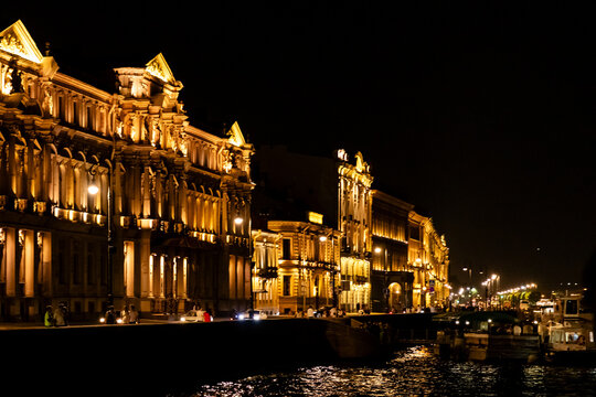 Saint Petersburg, Russia. Illuminated historic buildings along Neva riverbank at night, showcasing architectural details and reflections in the water