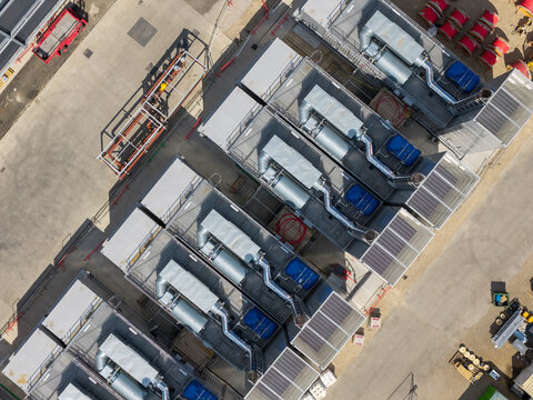 Aerial view of a data center facility with industrial cooling units, ventilation systems, and metal structures on a concrete site in the United Kingdom.