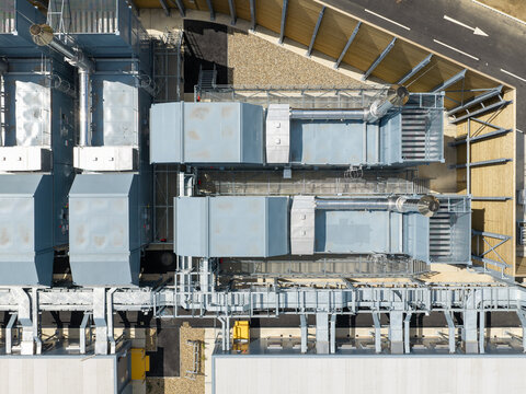 Aerial view of a data center featuring industrial cooling units, complex metal piping, and ventilation systems on a paved site in the United Kingdom.